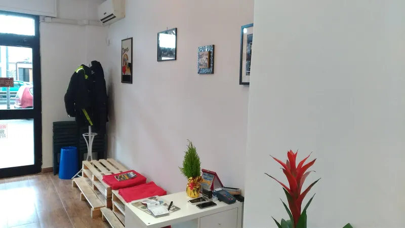 L'ingresso del salone con la panca d'attesa in legno, i cuscini rossi e le cornici alle pareti
